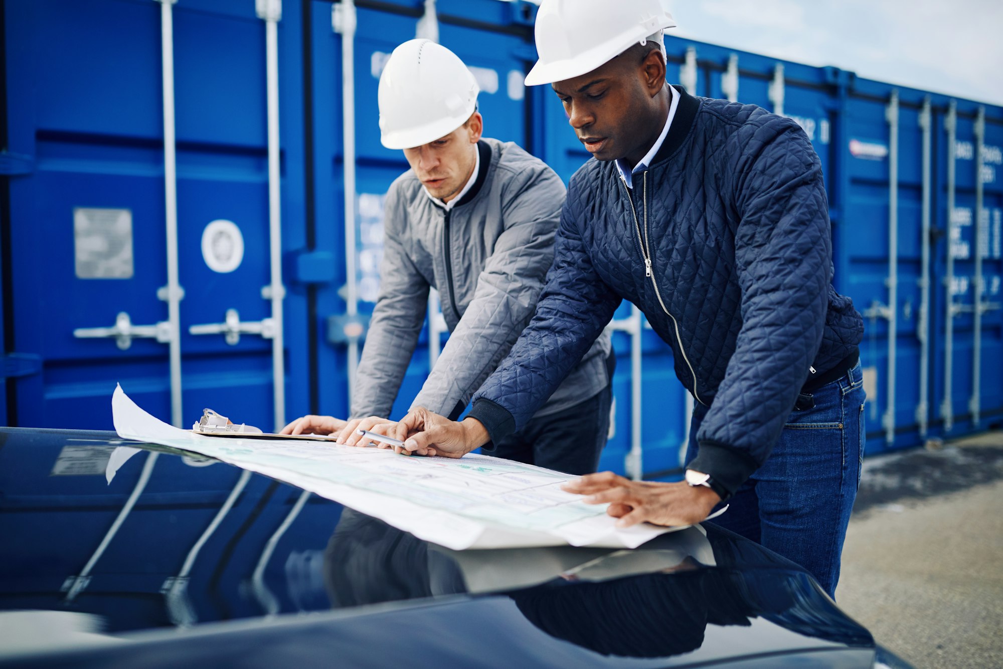 Two engineers discussing building plans together in a freight yard